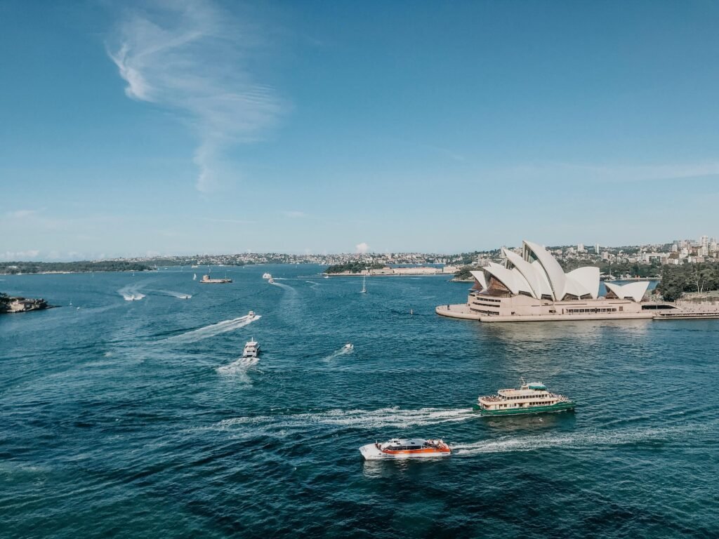 Aerial view of Sydney Opera House with boats in the vibrant Sydney Harbour during the day.